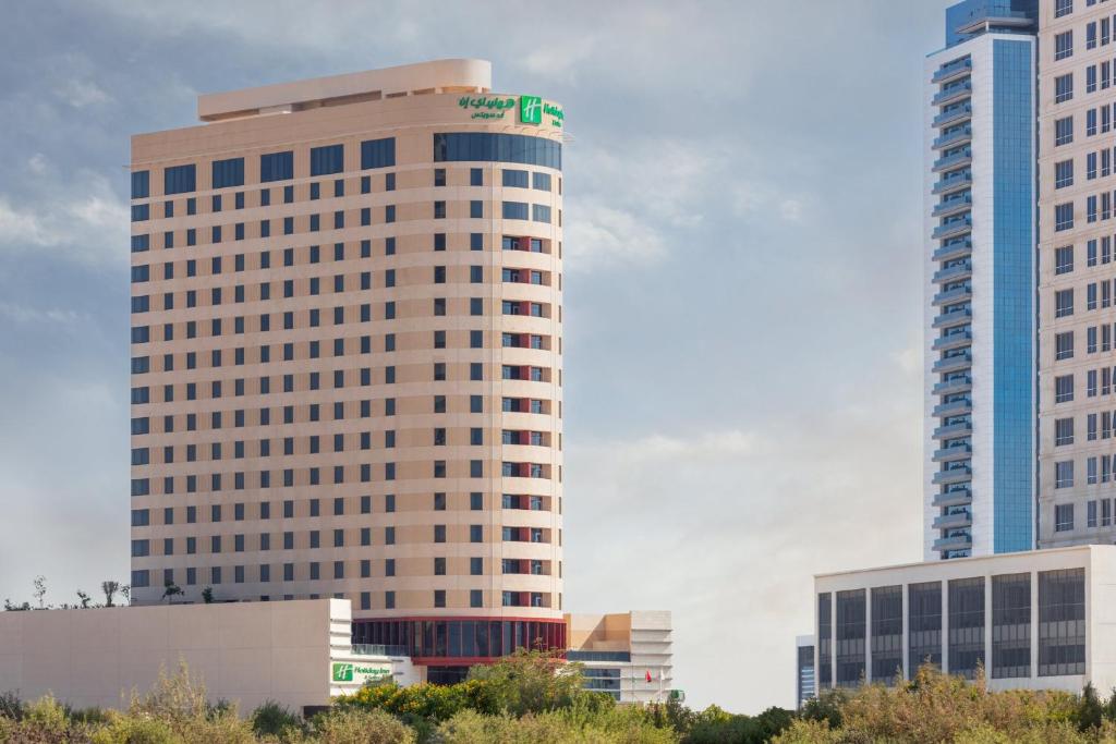 迪拜Holiday Inn & Suites - Dubai Science Park, an IHG Hotel的上面有绿色标志的高楼