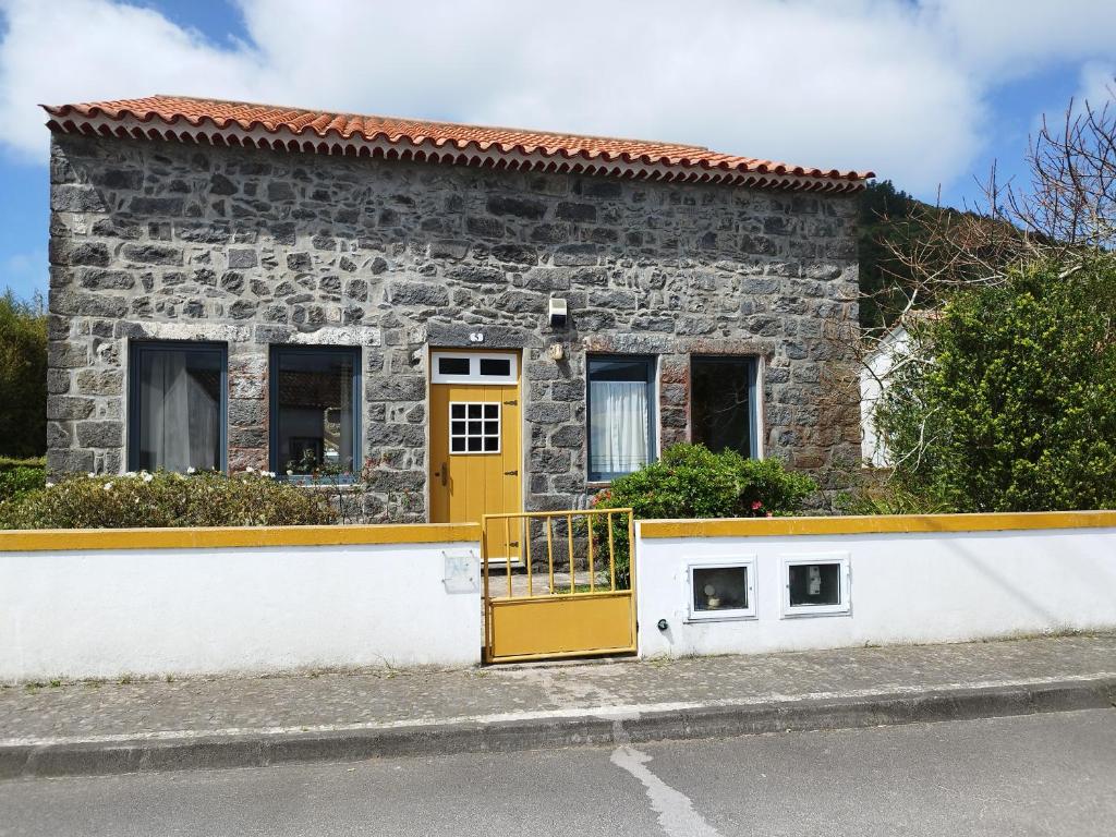 七城Casa dos Platanos-Family Home的街上的石头房子,有黄色的门