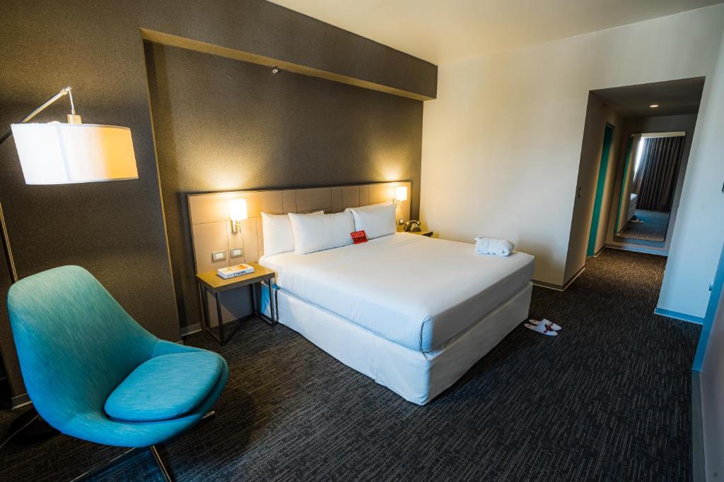 塔克纳BTH Rebel Tacna的一间卧室配有一张大床和一张蓝色椅子