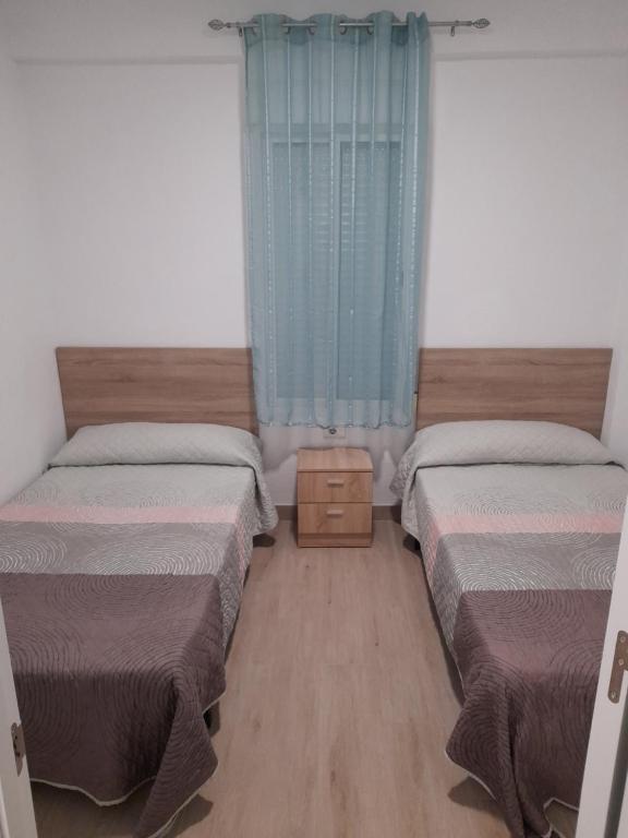 贝利雷瓜尔德Apartamentos playa de bellreguard,gandia,oliva,denia,benidorm的一间卧室配有两张床和蓝色窗帘