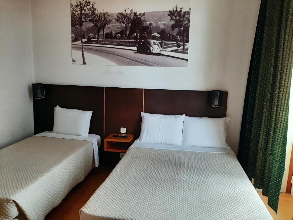科英布拉艾维斯住宅旅馆的一间设有两张床的客房,墙上挂着一张照片