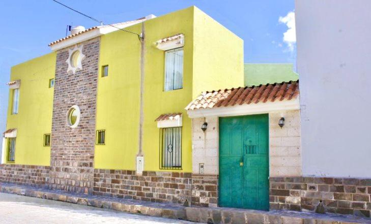 YanqueChuklla的一条黄色的建筑,在街上有一扇绿色的门