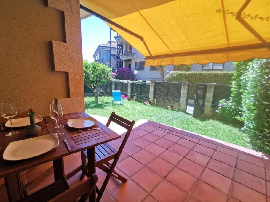 尼格兰P° Olmos, Panxón, bajo con jardín privado的庭院里配有一张带椅子和遮阳伞的木桌