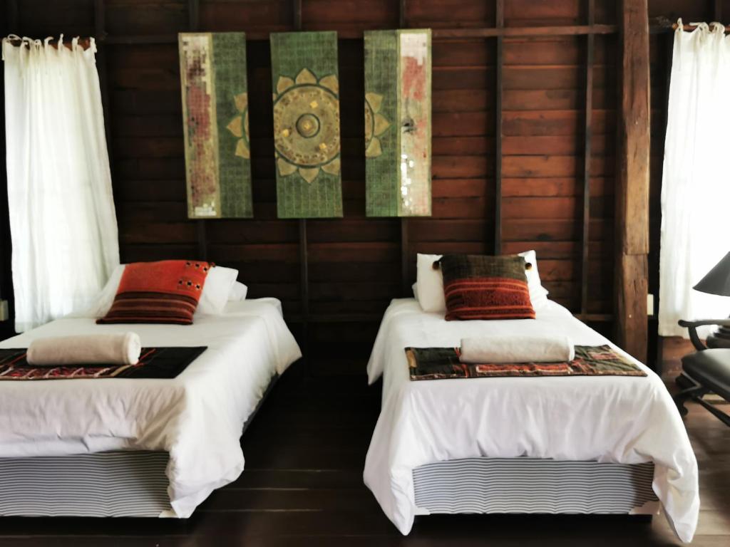 萨科特山Jasmine Hills Lodge的配有木墙和窗户的客房内的两张床