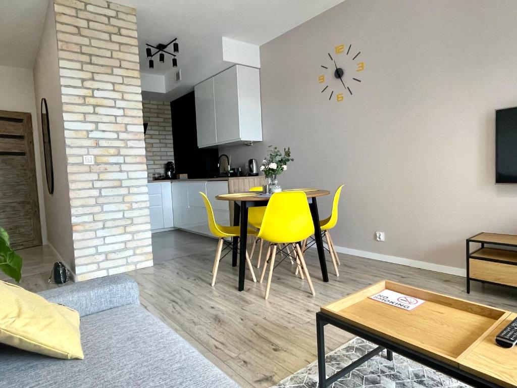 马佐夫舍地区新庄园Apartments Sleep & GO Modlin Airport的客厅配有桌子和黄色椅子
