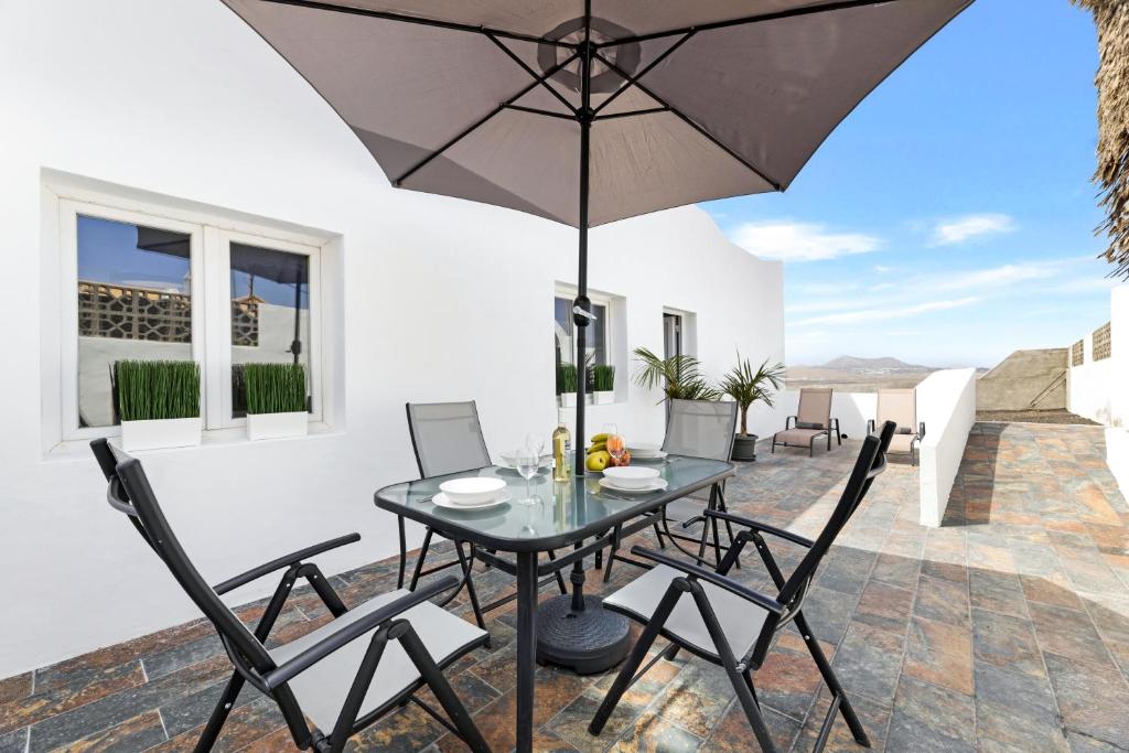 特吉塞Home2Book Charming Apartment Teguise, Terrace的庭院配有桌椅和遮阳伞。