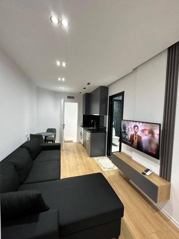 地拉那CozyStayApartments的客厅配有黑色沙发和平面电视。