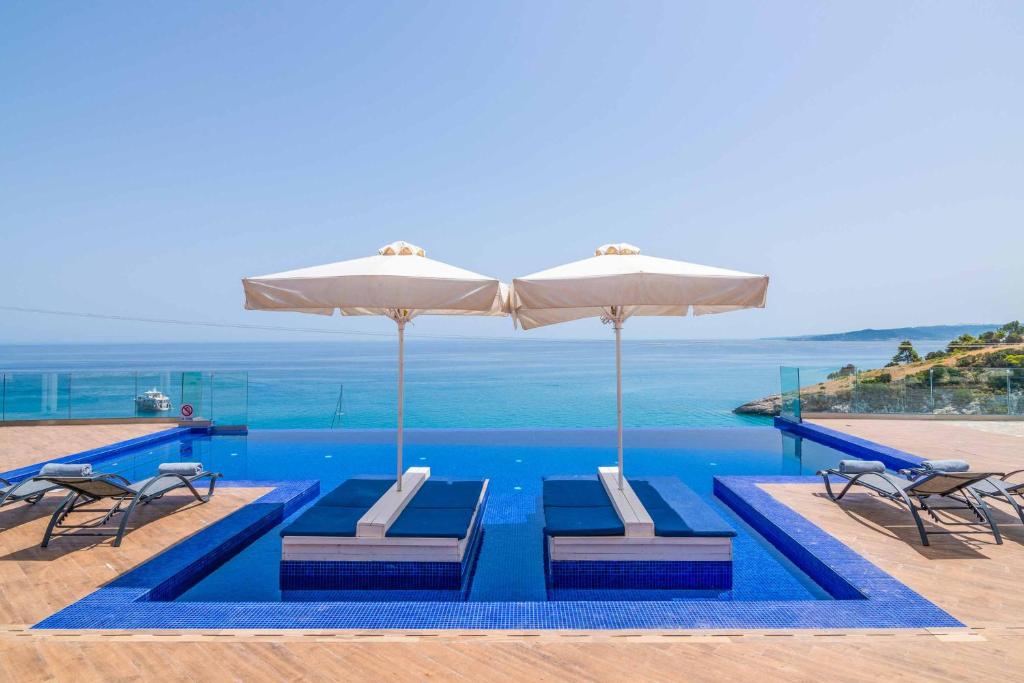 SkináriaVilla Orient Platinum的一个带两把椅子和遮阳伞的游泳池