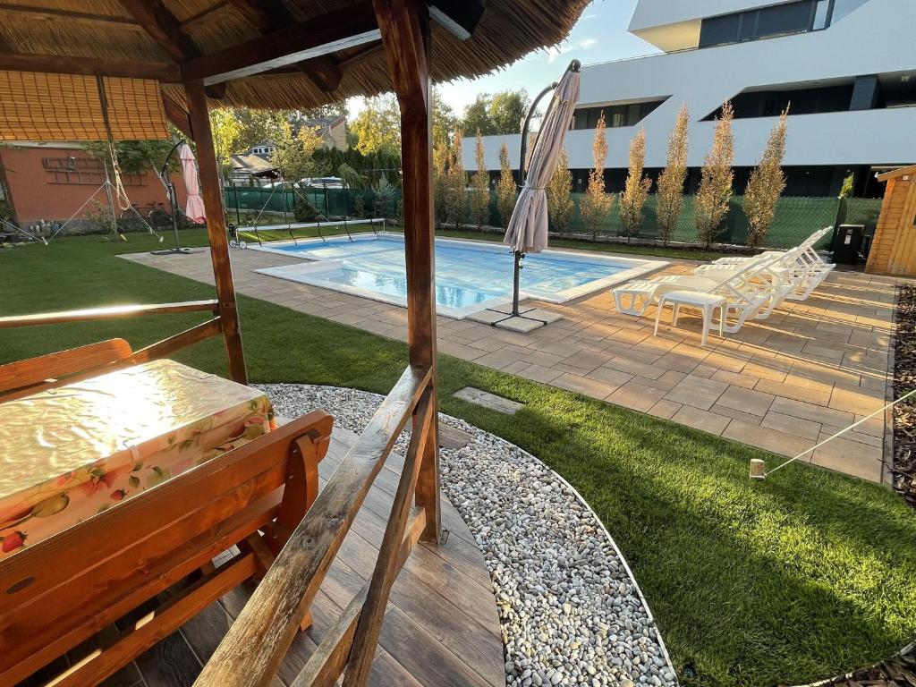 鲍洛通塞迈什Szemes Villa的一个带长凳和遮阳伞的庭院和一个游泳池。