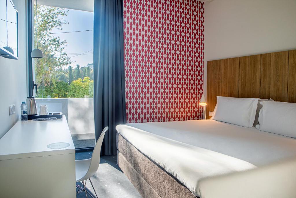 里斯本Stay Hotel Lisboa Aeroporto的客房设有床、书桌和窗户。