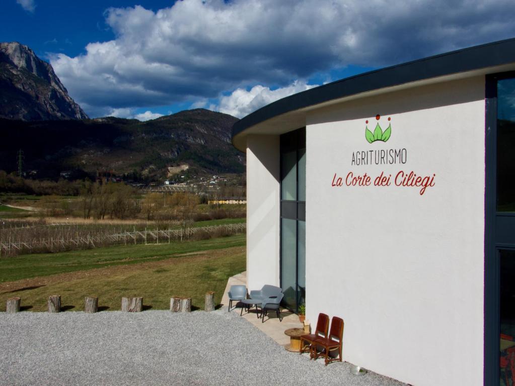 特伦托Agritur La Corte dei Ciliegi的白色的建筑,有椅子和标志