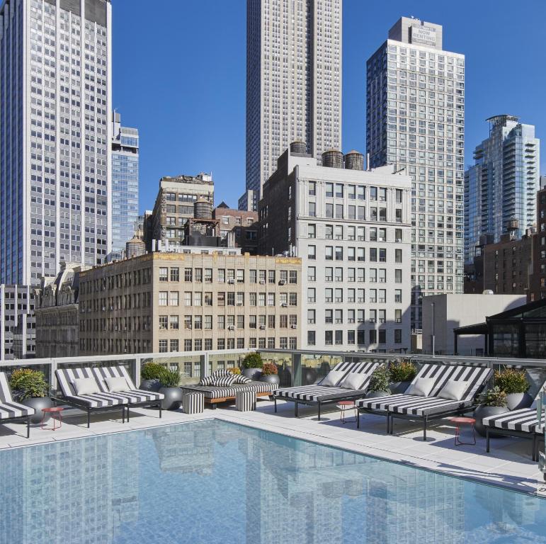 纽约Virgin Hotels New York City的一个带躺椅的游泳池,享有城市天际线
