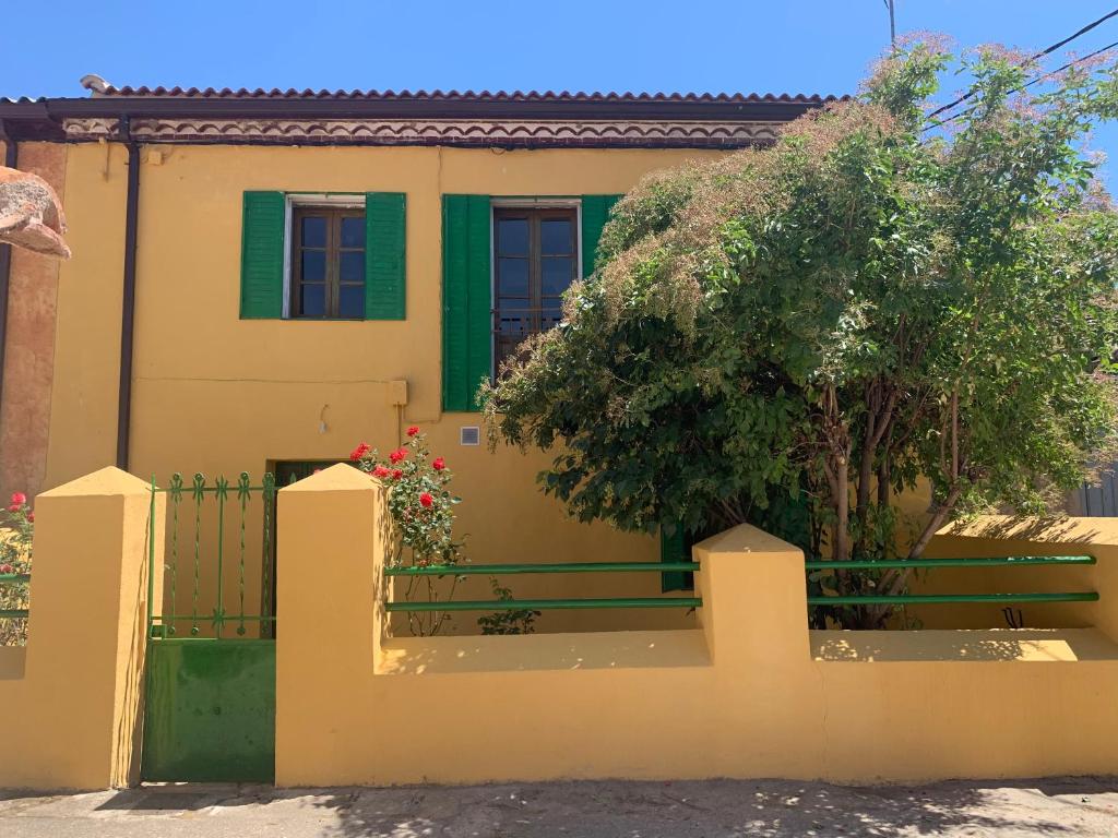 Alameda del ValleLa Toscana en Lozoya的黄色的房子,设有绿门和栅栏