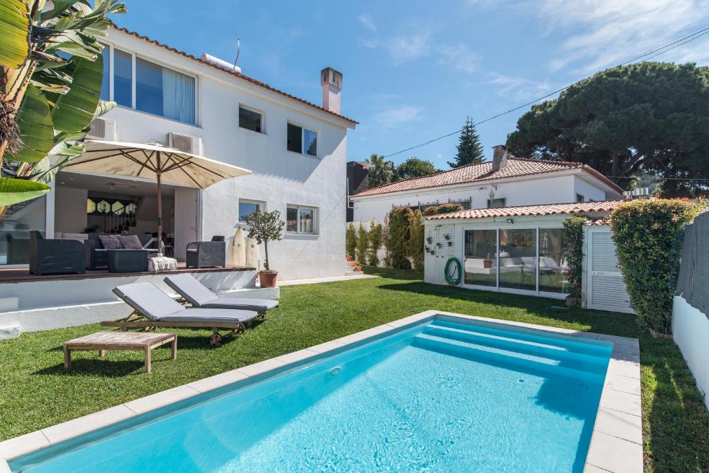 卡帕里卡海岸Caparica Dream Vila的一个带游泳池和房子的后院