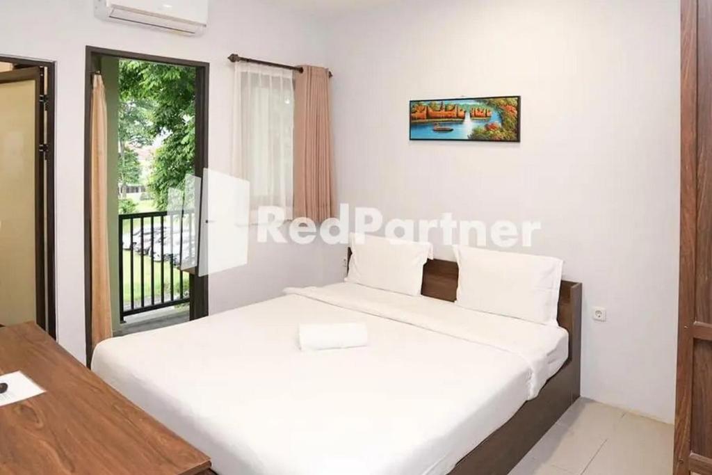 巴图Panorama İnn Residence Batu Mitra RedDoorz的一间卧室配有一张床、一张桌子和一个窗户。
