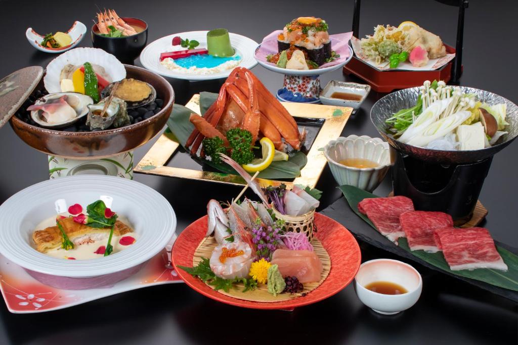 鹤冈市尤拉温泉八乙女日式旅馆 的盘子上装满不同种类食物的桌子