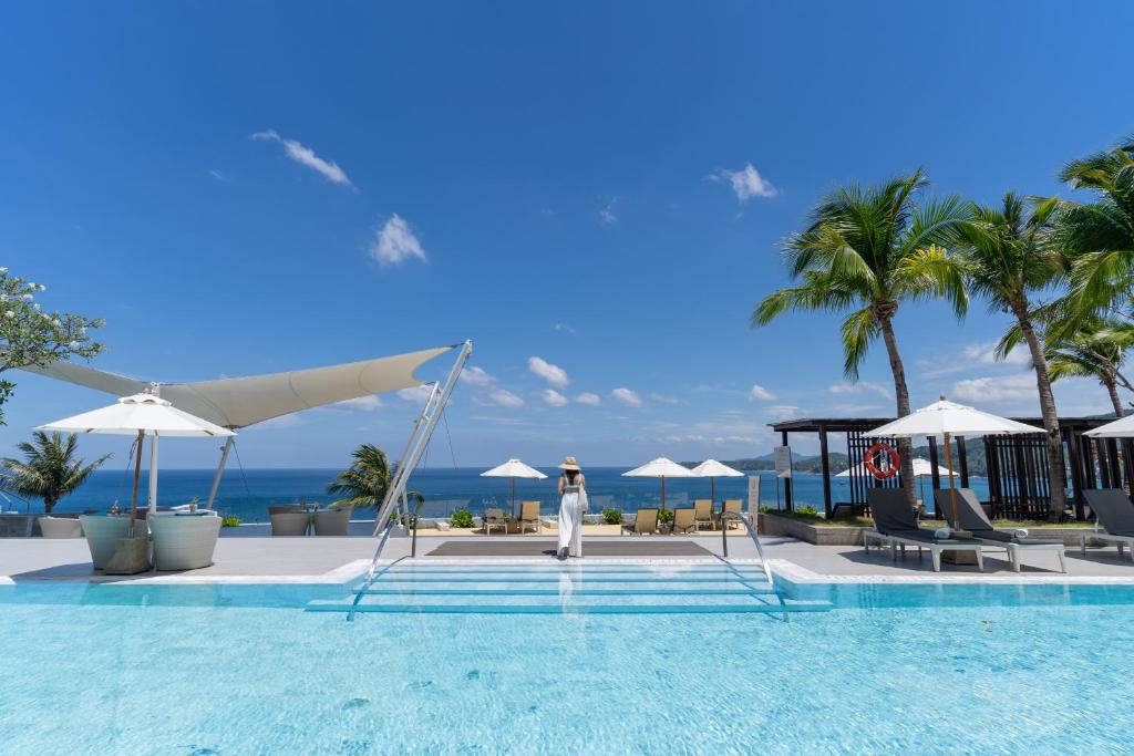 卡马拉海滩Cape Sienna Phuket Gourmet Hotel & Villas - SHA Extra Plus的站在度假村游泳池旁的女人