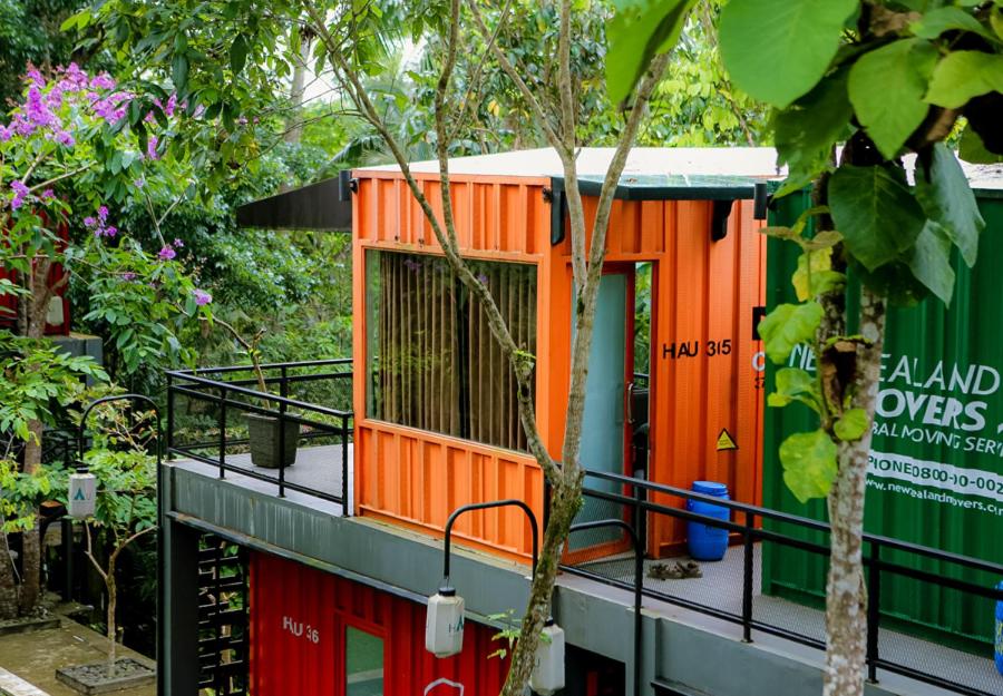庞岸达兰Hau Eco Lodges Citumang Pangandaran的一座橙色的小房子,在一座建筑的一侧
