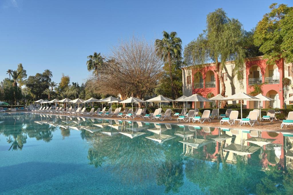 马拉喀什Iberostar Club Palmeraie Marrakech All Inclusive的一个带椅子和遮阳伞的大型游泳池