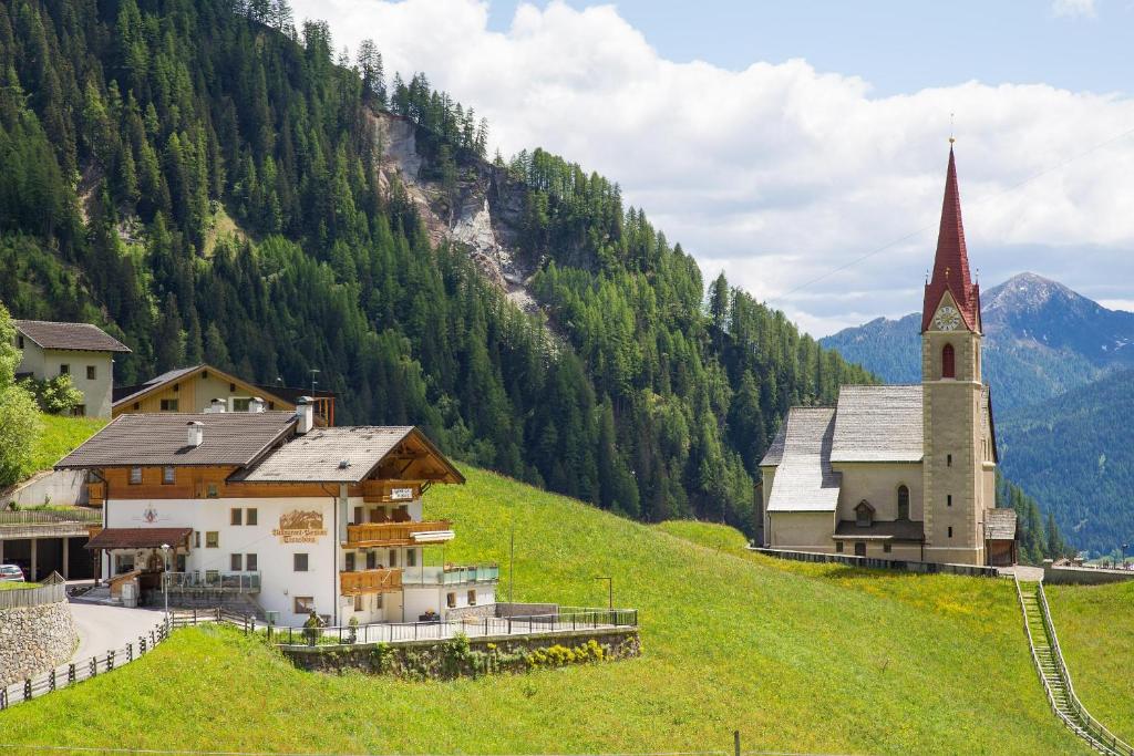 Corvara in PassiriaGasthof Trausberg的山丘上的小村庄,有教堂