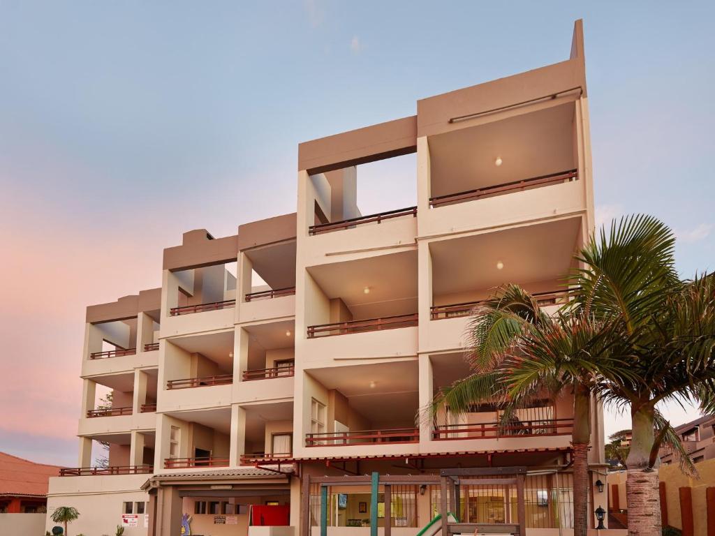马盖特First Group Costa Smeralda的公寓大楼前方有棕榈树