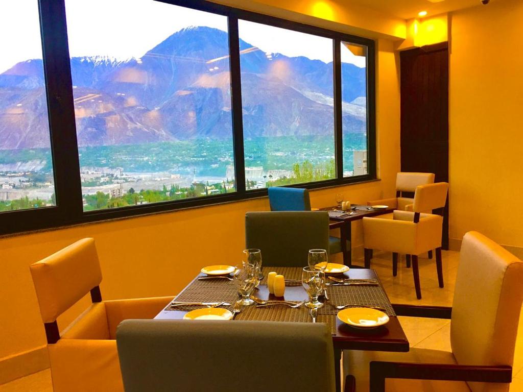 吉尔吉特Avari Xpress Gilgit的餐厅设有桌椅和大窗户。