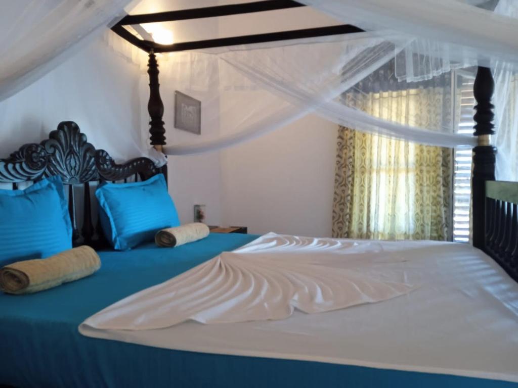 坦加拉Pearl Cave Cabanas & Resturant的一间卧室配有一张带蓝色枕头的天蓬床