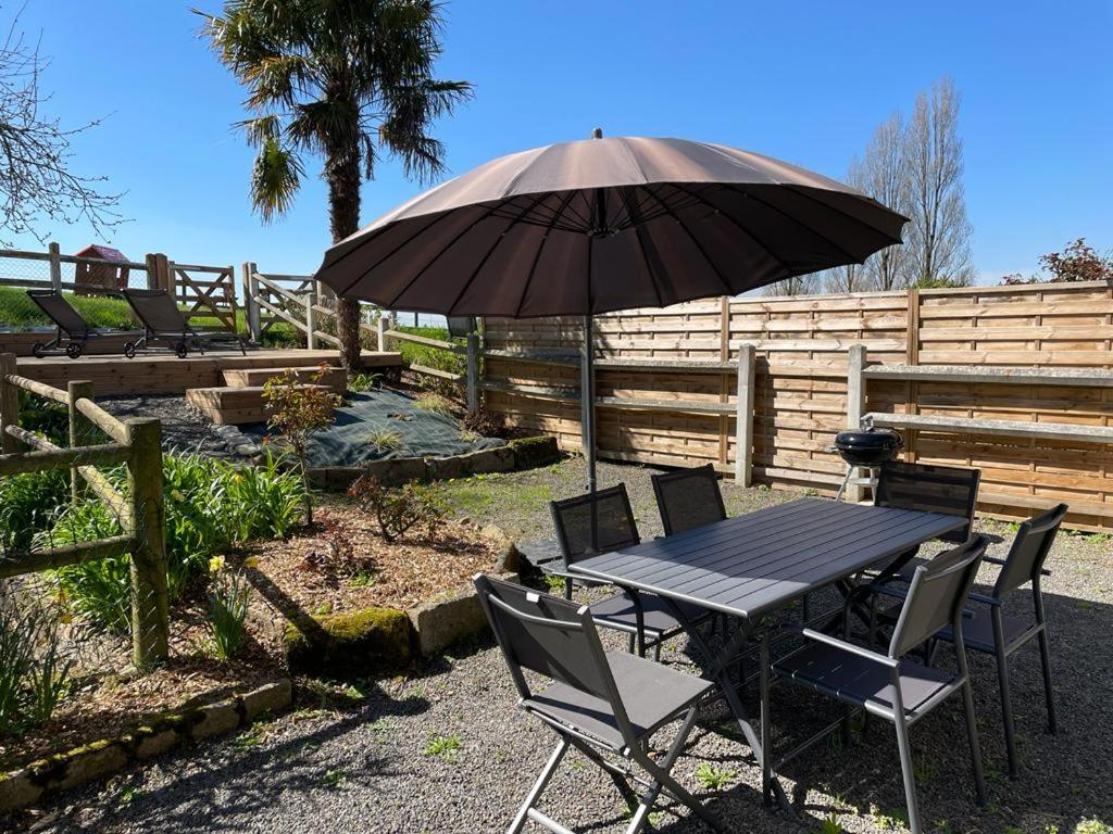 阿夫朗什Maison chaleureuse avec terrasse et vue baie的院子里的桌椅和雨伞