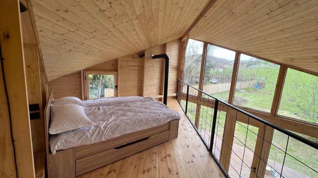 OzurgetʼiDumbo Eco Camp的带阳台的木制客房内的一张床位