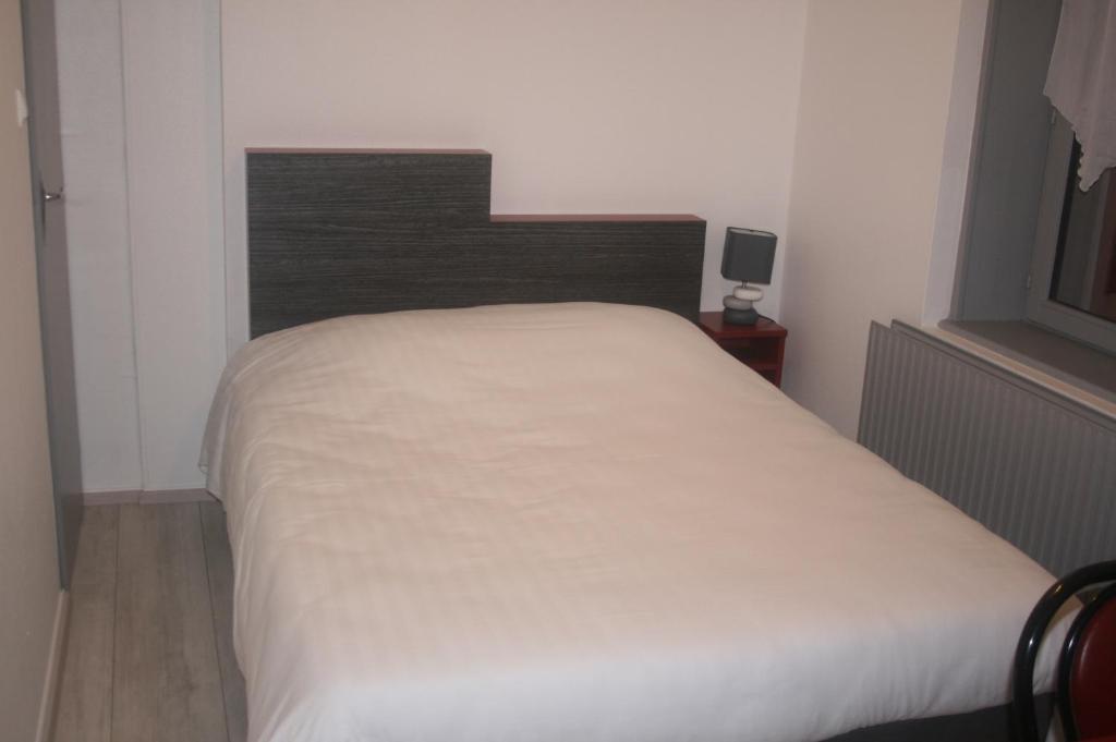 RambervillersLe P'tit Bouchon的卧室配有白色的床和木制床头板