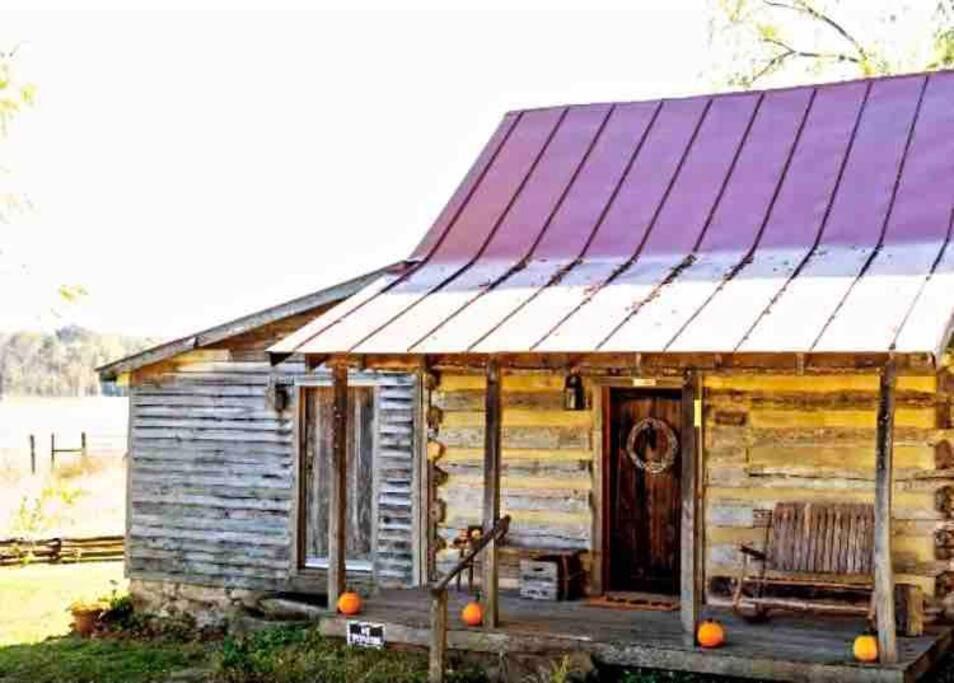 Historic 1850's Cosmic Cabin的一座带门廊和椅子的古老木屋