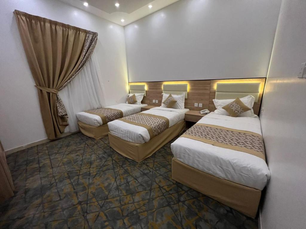 麦地那فندق ريسان的酒店客房设有三张床和窗户。