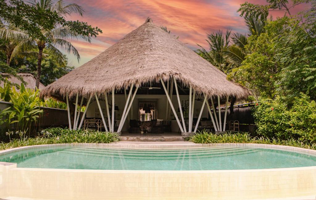 丹戎Beach Villas Lombok的茅草屋顶的度假游泳池