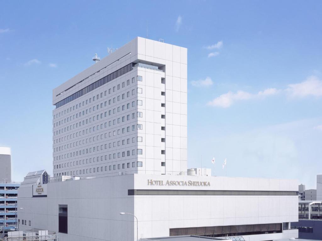 静冈阿索西亚静冈酒店(Hotel Associa Shizuoka)的一座白色的大建筑,上面有标志