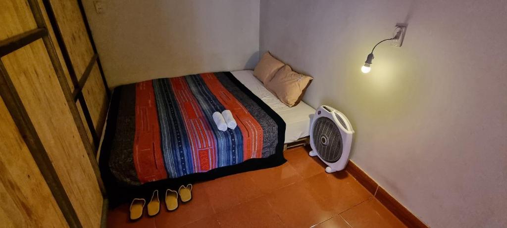 河江Rainbow House Ha Giang的小房间设有一张带风扇和鞋子的床