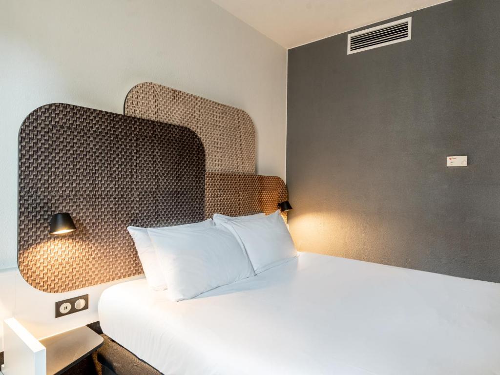 马赛B&B HOTEL Marseille Prado Parc des Expositions的卧室配有白色的床和床头板