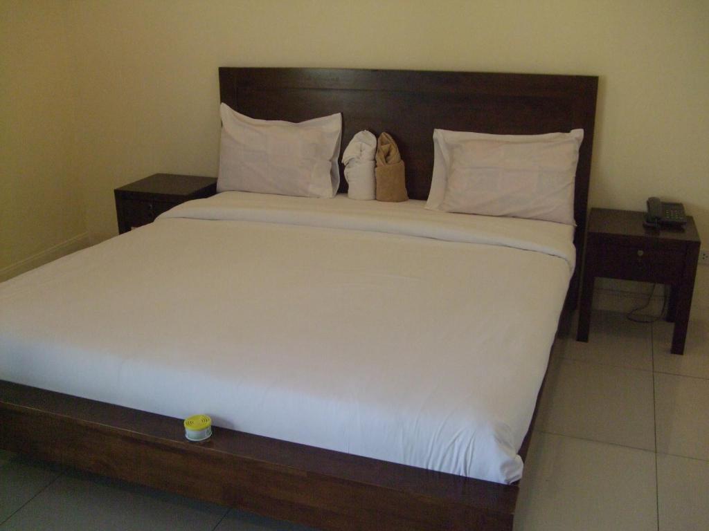芭堤雅市中心班齐提玛公寓的一间卧室配有一张带2个床头柜的大型白色床