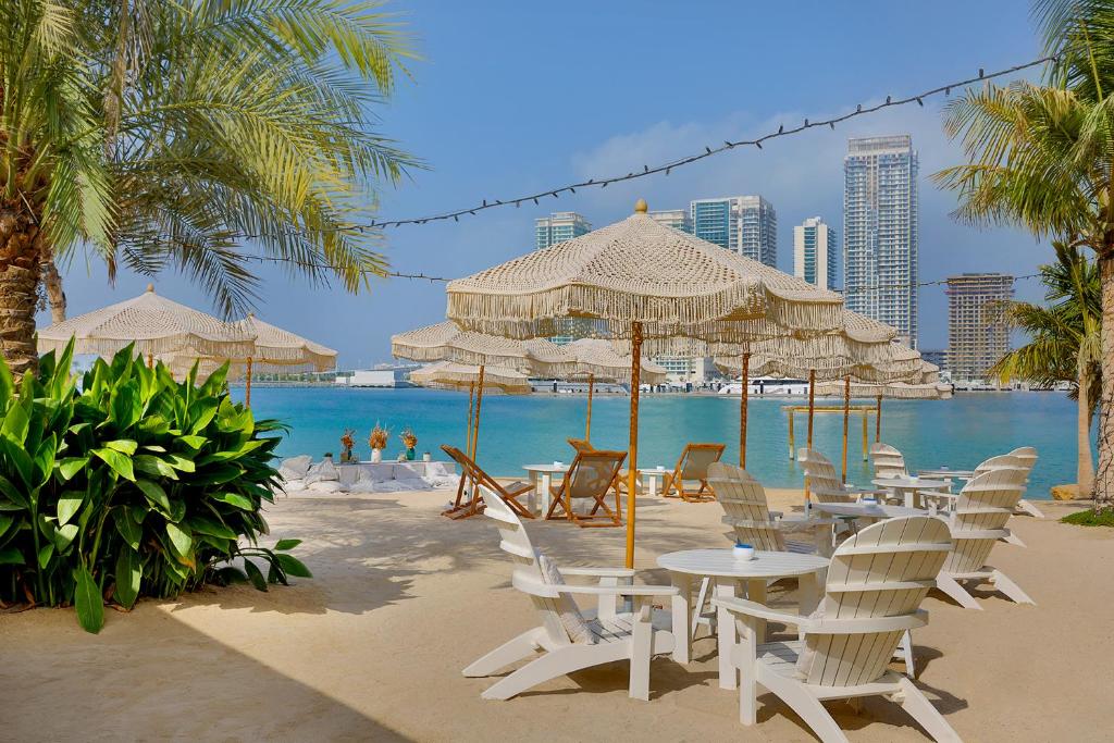 迪拜W Dubai - Mina Seyahi的海滩上设有桌椅,大海上设有沙滩