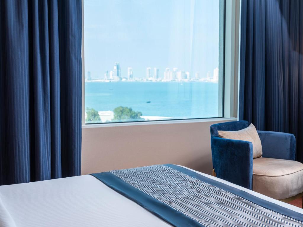 多哈艾尔瑞安瑞塔杰酒店的卧室配有床、椅子和窗户。