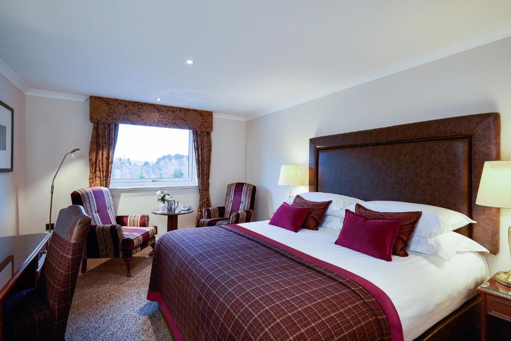 阿维莫尔Macdonald Highlands Hotel at Macdonald Aviemore Resort的配有一张床、一张书桌和一扇窗户的酒店客房