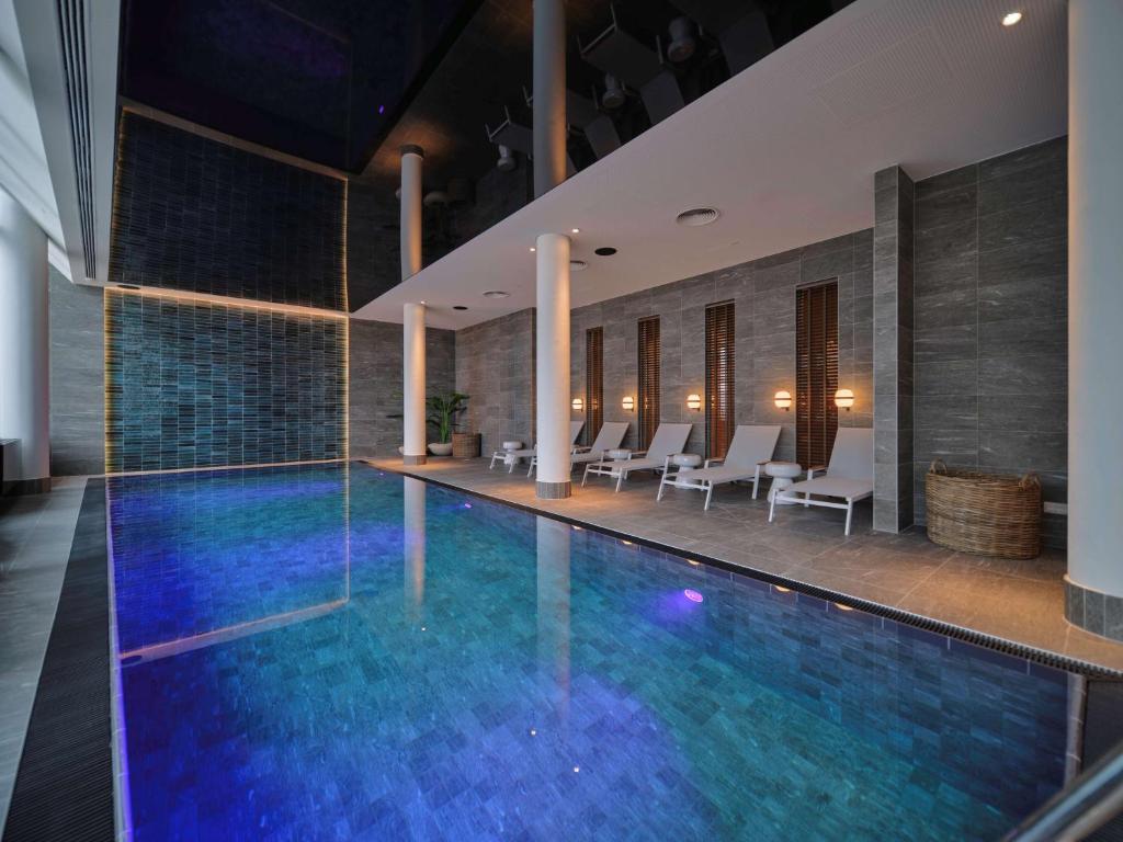 维也纳Adina Apartment Hotel Vienna Belvedere的一座带白色椅子的酒店游泳池