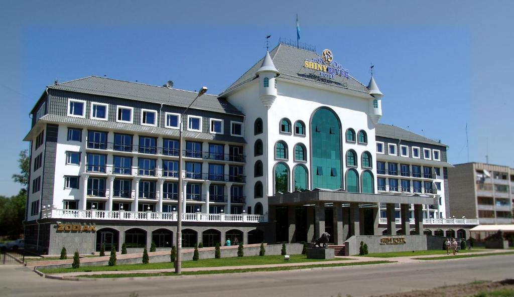 乌斯季卡缅诺戈尔斯克Shiny River Hotel的街道拐角处的白色大建筑