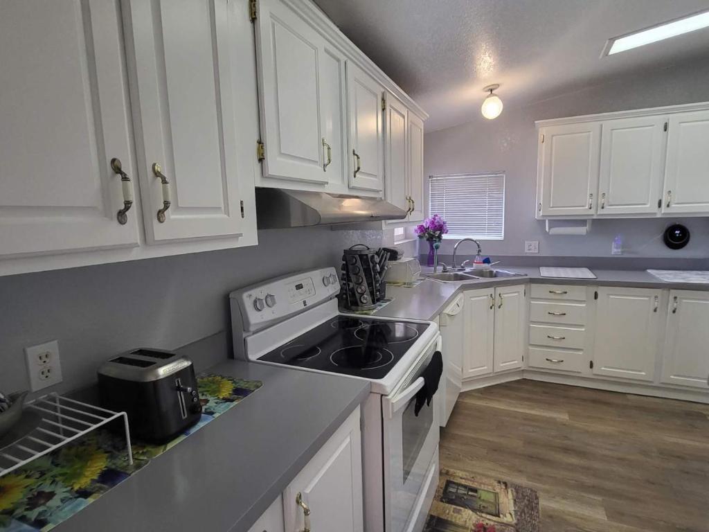 帕伦普Sun Angel House #1 Pahrump的厨房配有白色橱柜和炉灶烤箱。