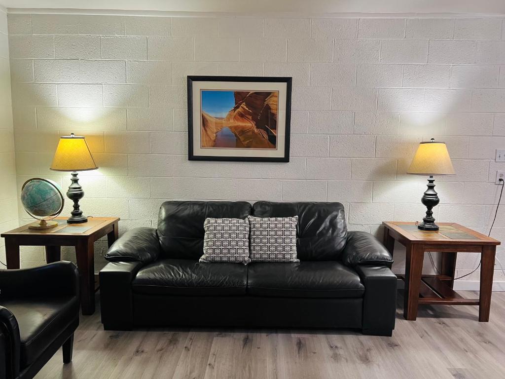 佩吉Lake Powell Motel & Apartments的客厅里一张黑色皮沙发,配有两盏灯