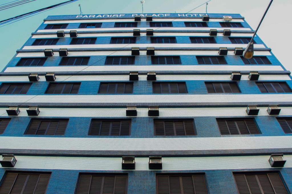 阿帕雷西达Paradise Palace Hotel的一座高大的蓝色建筑,上面有标志