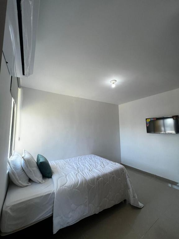 哥伦比亚港apartamento barranquilla villa campestre!的卧室配有白色的床和枕头。