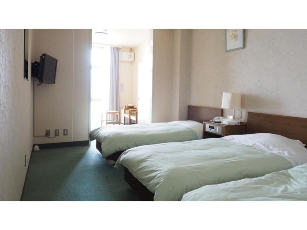 IkedaKokuminshukusha Shodoshima - Vacation STAY 59365v的酒店客房设有三张床和电视。