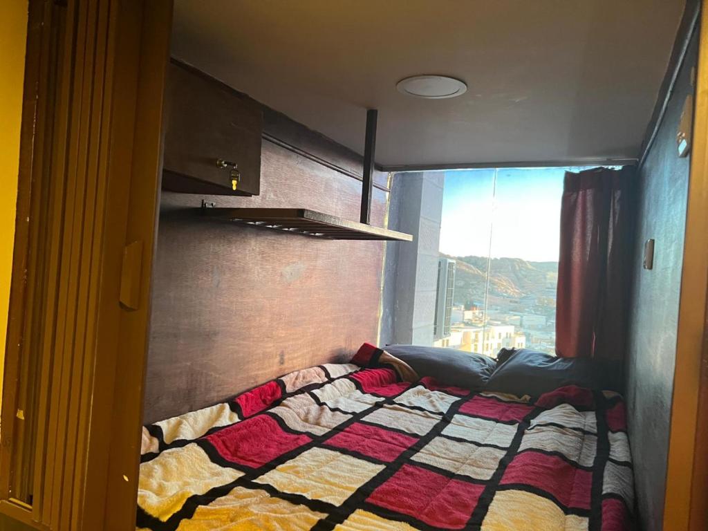 瓦迪穆萨Petra cabin Roof top hostel的一间卧室配有一张带被子的床和一扇窗户
