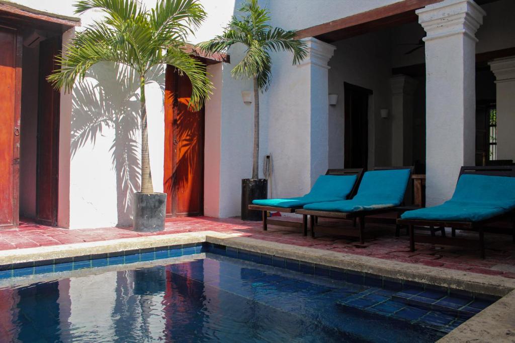 圣玛尔塔Casa Gaitana - Alma Hotels的一个带两把蓝色椅子和棕榈树的游泳池