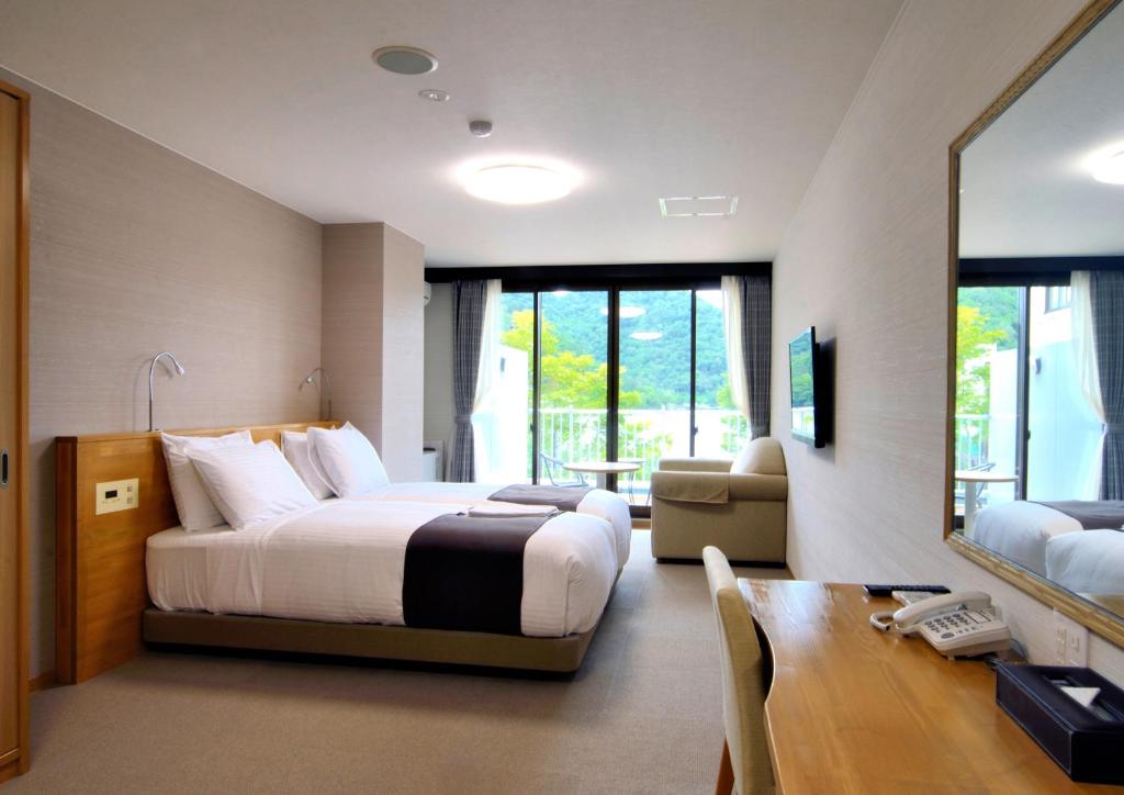 日光旅笼Nagomi温泉酒店(Hatago Nagomi)的酒店客房配有一张床铺、一张桌子和一张书桌。